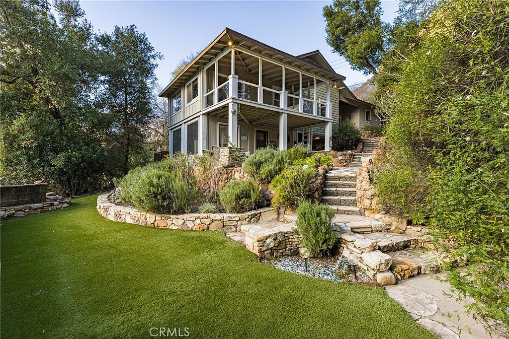Stone stairway leading to the wraparound porch through lush landscaping