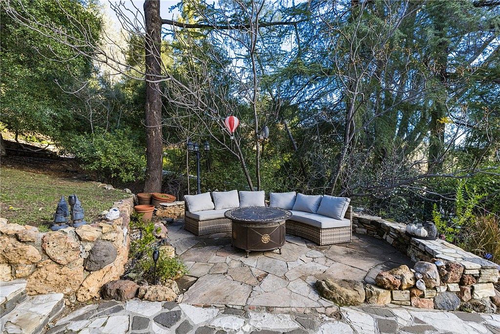 Stone firepit lounge area surrounded by mature oaks